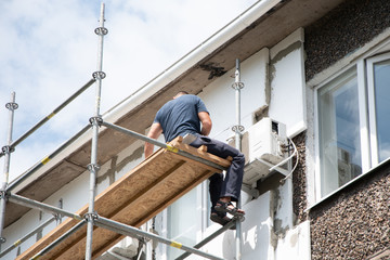 Thermal insulation of the exterior wall panel. Worker man insulates wall high-rise building.