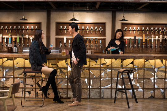 Happy friends having drinks and talking in bar