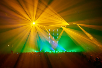 Play of lights from the stage of a music festival crowded with people who are dancing