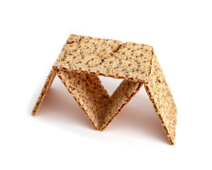 Сrunchy wheat rye brown crackers, house of cards, isolated on white background. Building house form food, playing with bread.