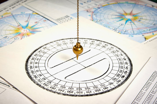 Astrological pendulum for tarot and astrological circle on the background of astrological charts and horoscopes