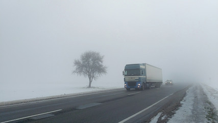 Fototapeta na wymiar Cars in the fog. Bad winter weather and dangerous automobile traffic on the road.