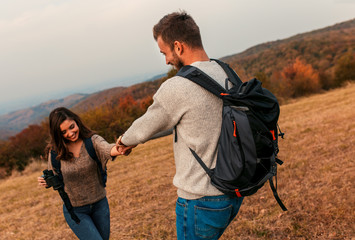 Young couple enjoying hiking in nature They are holding hands and laughing.