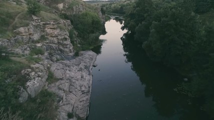 Thin stream stretching between two stony hills in the evening in summer