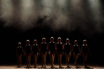 Ballet class on the stage of the theater with light and smoke. Children are engaged in classical...