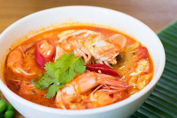 Thai spicy shrimp soup coconut milk (Tom Yum Kung) in a bowl with banana leaf in the background.