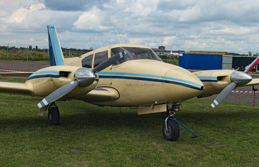 The two engine plane stands on the green grass in a cloudy day. A small private airfield in Zhytomyr, Ukraine