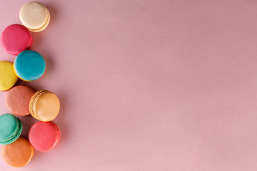 Sweet and colorful french macaroons on a pink background. Dessert is with tea or coffee.