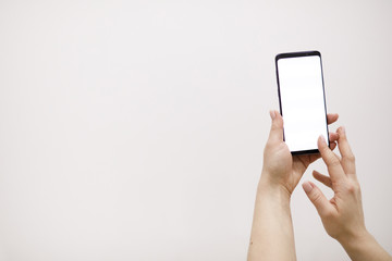 Female hand holding black cellphone with white screen.