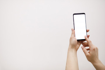 Female hand holding black cellphone with white screen.