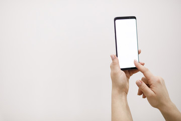 Female hand holding black cellphone with white screen.