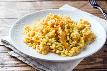 Vegetarian Oriental pilaf with rice and vegetables on a wooden table.