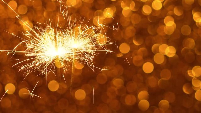 Sparkler burning against Golden Christmas or New Year festive background