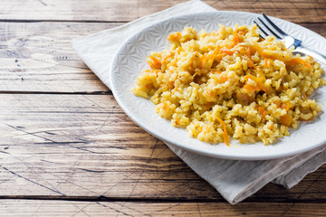 Vegetarian Oriental pilaf with rice and vegetables on a wooden table.