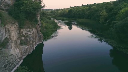 Curvy stream running between two stony banks with lily leaves at sunset in summer