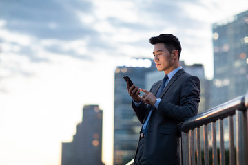 Young businessman using smartphone outdoors