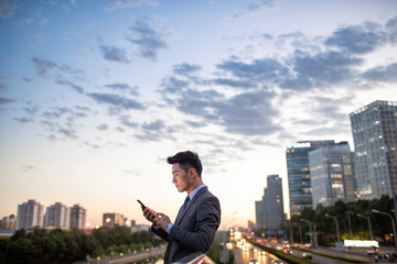 Side view of young businessman using smartphone outdoors