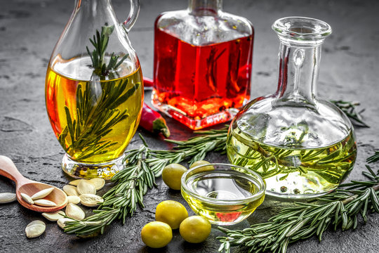 oil in carafe with spices, olives and chili on stone background