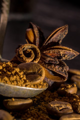 Stick of cinnamon and oriental spices, aniseed cocoa, with a vintage spoon of ground coffee and unroasted grains on a dark background. free space for your text. Close-up macro image.