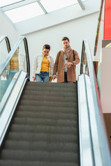 attractive girl and handsome man standing at top of escalator