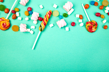 Colorful candies on pastel turquoise background. Flat lay