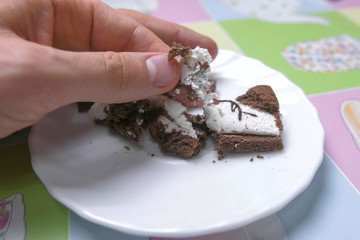 Man breaks chocolate and vanilla cake with his hand.