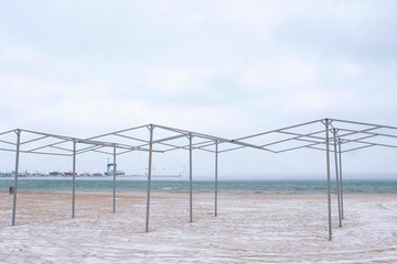 Beautiful view of the sand and snow storm on the beach in winter. Sea port.