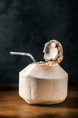 Coconut water drink on table. Cutting exotic fruits ready to serve as milk beverage. Healthy food with vitamin