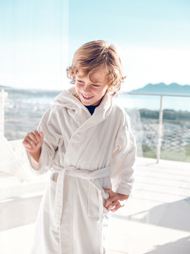 Cheerful boy in bathrobe standing on terrace