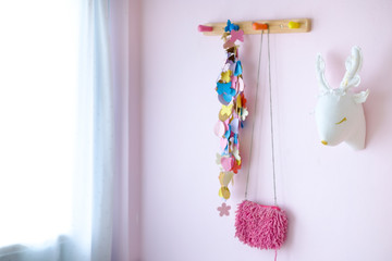 Pink shoulder bag and colourful heart with butterfly hang  wooden wall hanger in the room.