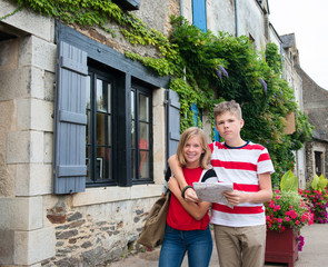 Teenagers travel concept. Children with map walking in the street of an old town, historical centre of the town, Rochefort-en-Terre, France