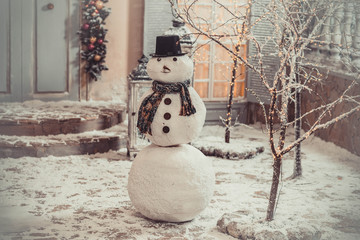  snowman in the yard is white in the evening on the background of the house New Year's yard Christmas landscape design winter magic snow joy