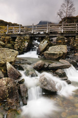 Naklejka premium Rustic bridge over a mountain cascade at Cwm Idwal in the Glyderau range of mountains in Snowdonia National Park North Wales