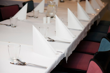 Laid tables with napkins for several guests. Empty chairs. Expect guests. Restaurant Reservations 