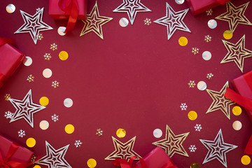 Silver and golden stars, red gift boxex, snowflakes on the red background. Place for your text.