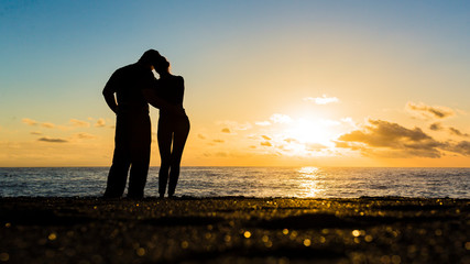 Silhouette of loving couple standing riverside and beautiful sunset background