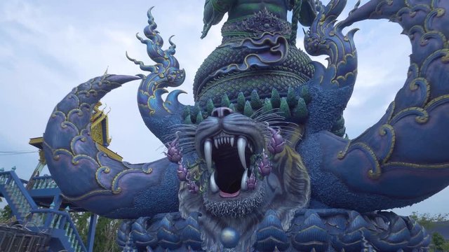 Blue sculpture of Thai ancient warrior standing near the temple. The mouth of the tiger. Thailand. Temple of the Blue Buddha. Chiang Rai province.