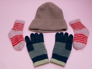 set of winter must have cloth accessories - woolen hat, gloves and socks. on pink background