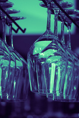 A group of vine glasses hanging in a night club bar.  Restaurant bar glass shelf.
