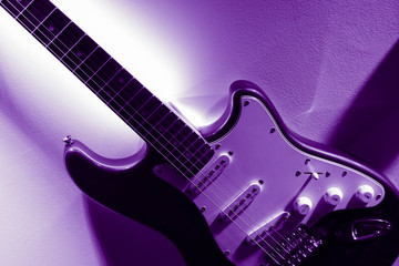 Fototapeta premium Abstract electro guitar closeup, purple light background.