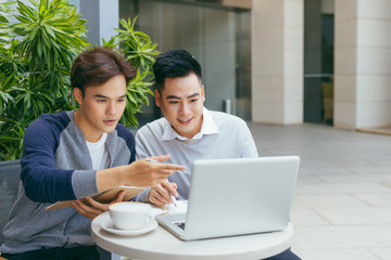 Business people looking at document and discussing while at cafe. Two businessmen working together on business report at coffee shop. - Image