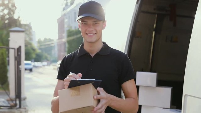 Delivery Service. Courier With Box In Hands Near Car Outdoors