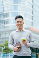 Young businessman standing with coffee in hand - Image