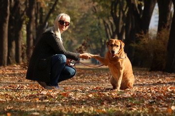 Adult woman having nice moments with her dog at city park