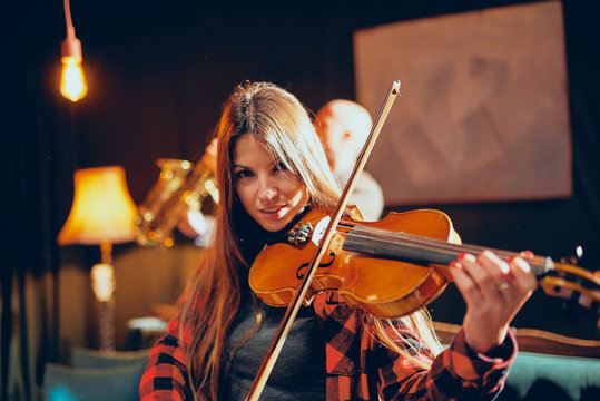 Close up of beautiful brunette playing violin. Home studio interior.