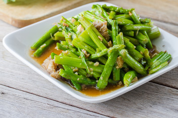 stir-fried asparagus in plate on wooden table.