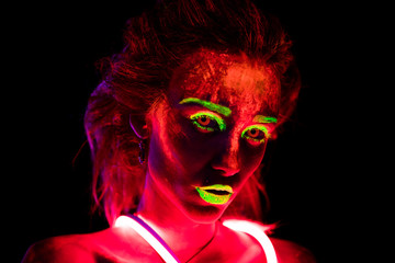 Portrait of a beautiful young sexy girl in neon lent with ultraviolet paint on her body. Pretty woman with glowing bodyart in black lamp light