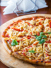 Pizza on wooden plate at restaurant table. Close up