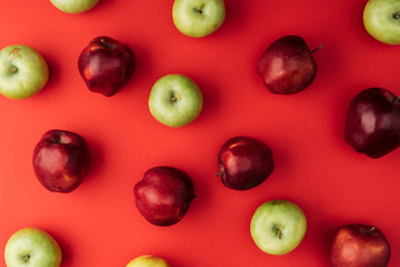 top view of delicious large multicolored apples on red background