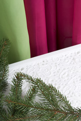 Spruce branches on a white tracery background. Against the backdrop of curtains of lime and pink.